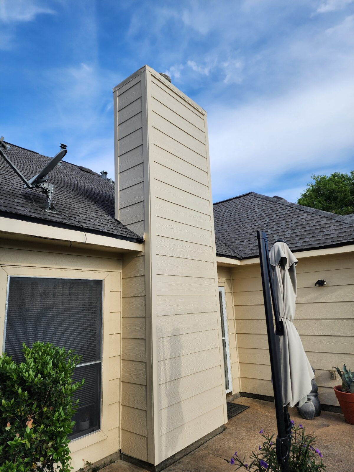 Repainted chimney chase and cream siding under blue sky