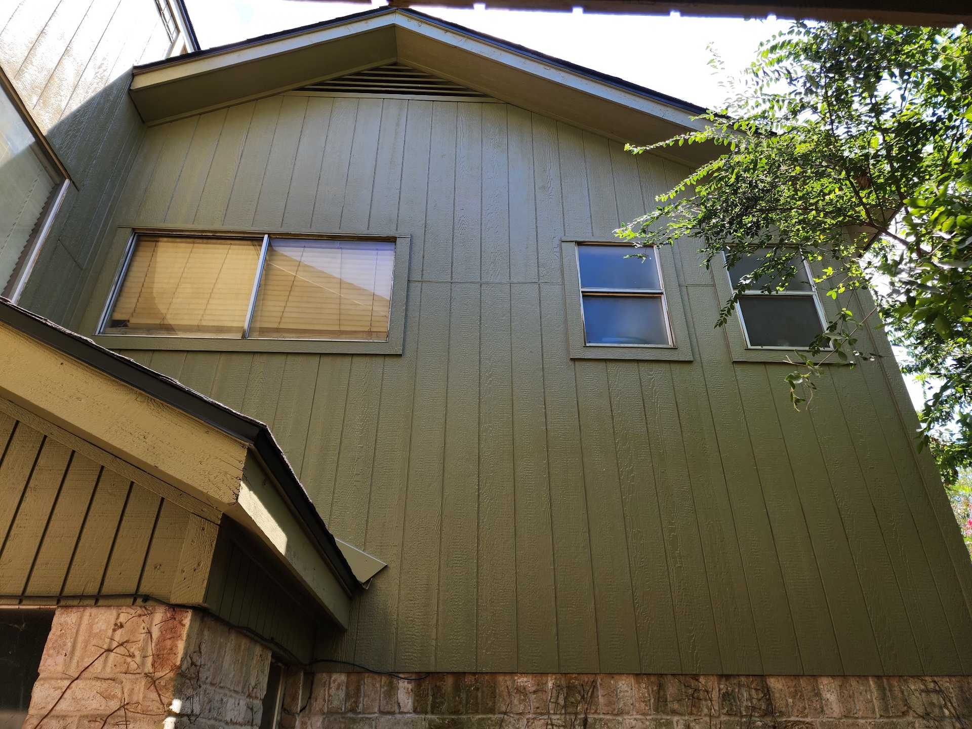 Sage green painted board and batten siding with fresh trim on a two story Houston home